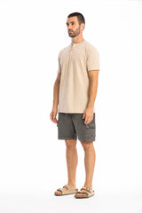 Man wearing a beige shirt and gray shorts on a white background