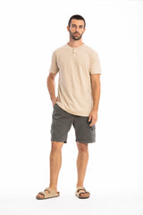Man wearing a beige shirt and gray shorts on a white background