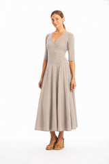 Woman wearing a V-neck long grey dress with 3/4 sleeves on a white background