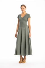 Woman wearing a long V-neck green dress with short sleeves on a white background