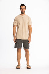 Man wearing a beige shirt and gray shorts on a white background