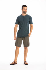 Man wearing a ocean blue buttoned t-shirt and linen shorts on a white background