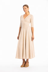Woman wearing a V-neck long light beige dress with 3/4 sleeves on a white background