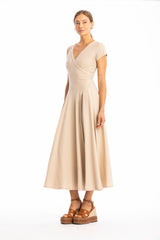 Woman wearing a long V-neck beige dress with short sleeves on a white background